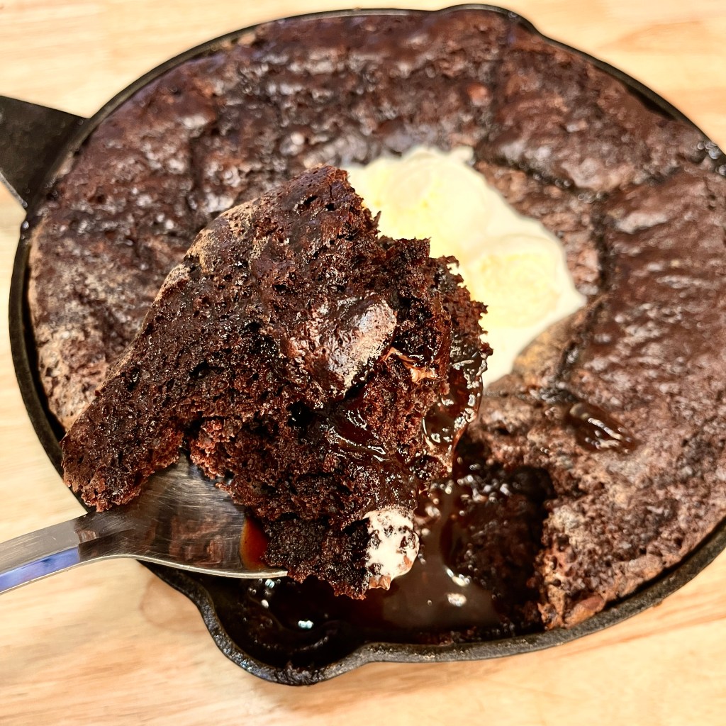 close up scoop of fudgy chocolate pudding cake. Moist chocolate cake with gooey fudge dripping down. 