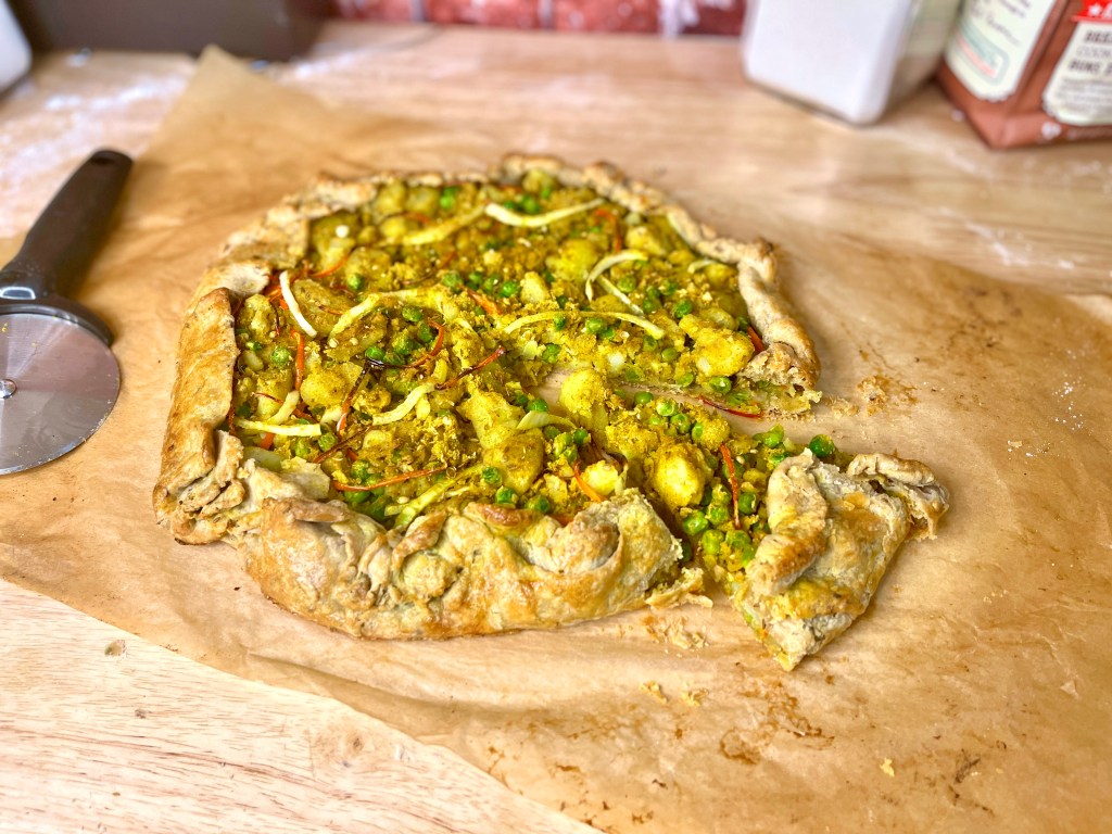 Free form pie. Golden brown crust with golden potatoes, green peas, slivers of onion and peppers. 