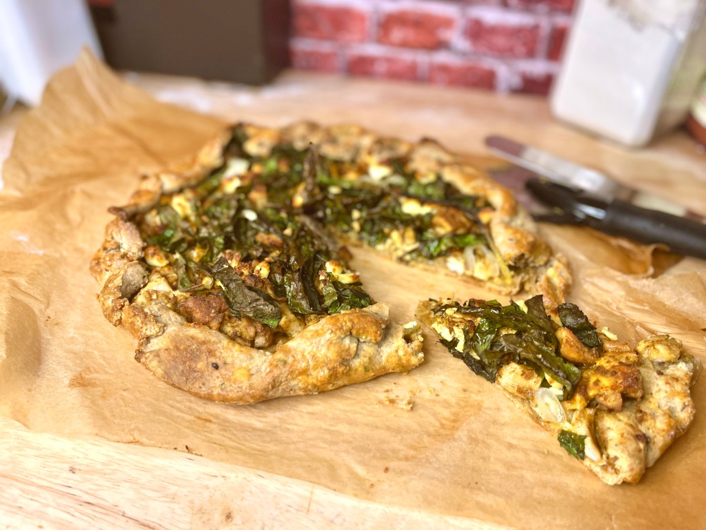 Golden brown whole wheat crust galette with chicken tandoori, swiss chard, and paneer. 